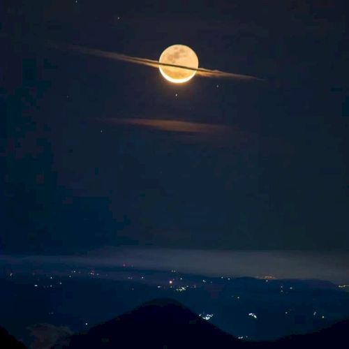 A bright moon over dark mountain peaks at night, framed by a glowing halo and a thin streak of light like a comet.