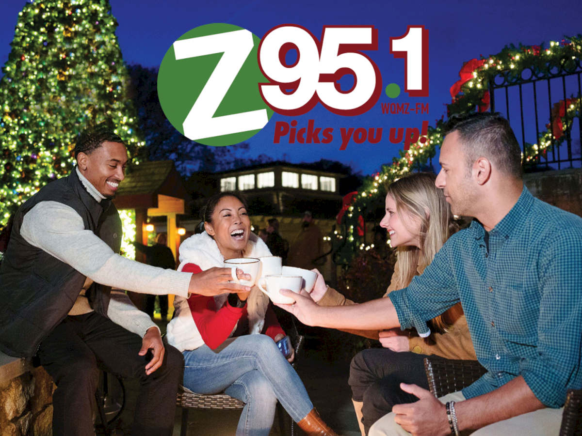 A festive holiday party with friends toasting, featuring WOMZ-FM 79.5.1 and &ldquo;Picks you up!&rdquo; on the screen.