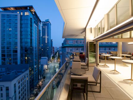 Modern rooftop terrace with outdoor seating overlooking downtown skyscrapers at dusk.